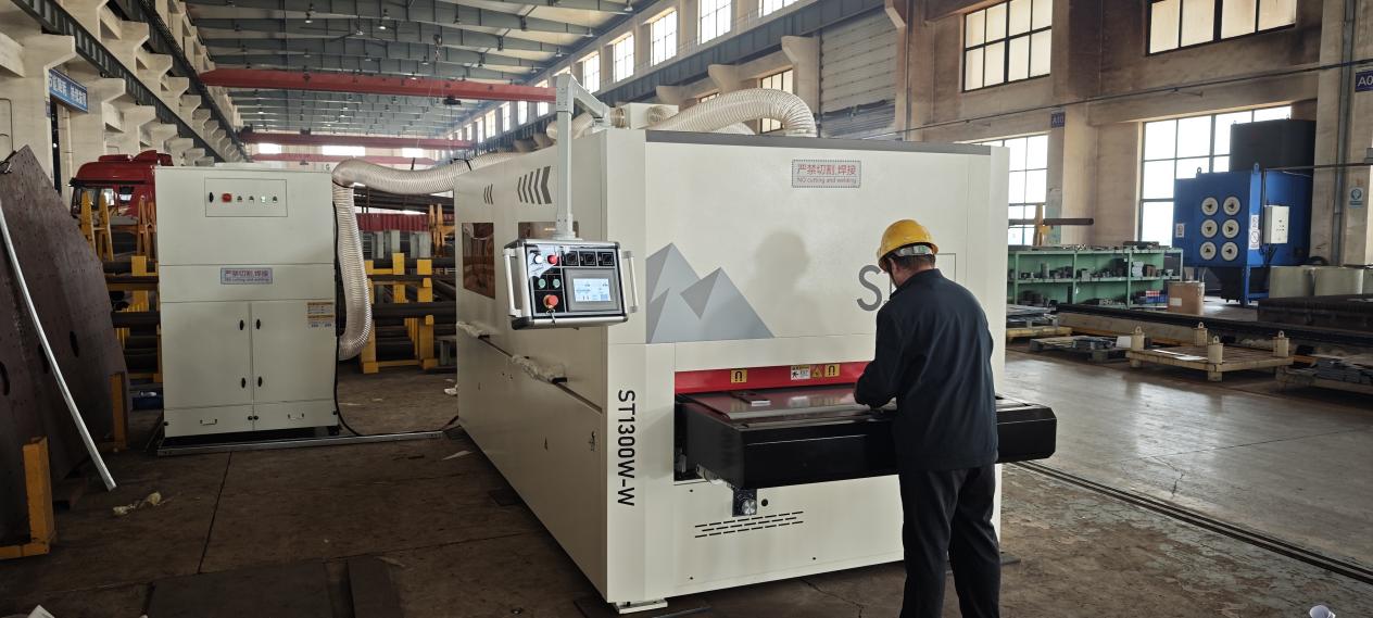 Operator using a custom metal finishing machine for sheet metal deburring and surface finishing in the manufacturing workshop