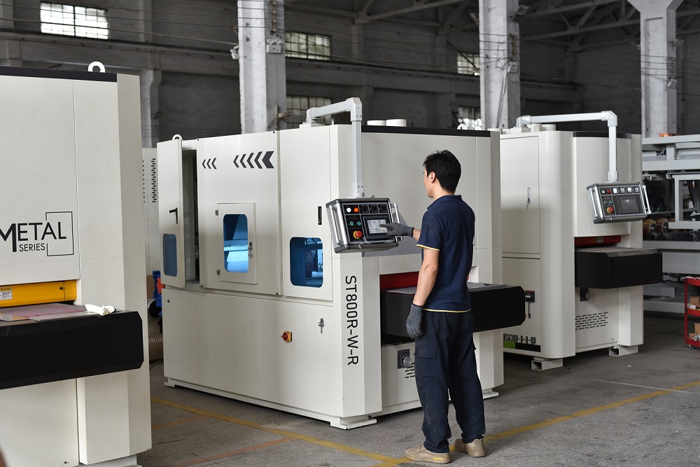 Worker operating a steel polishing machine for industrial metal surface finishing