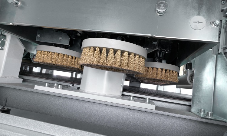 Rotary wire disc brushes inside a through-feed conveyor deburring machine